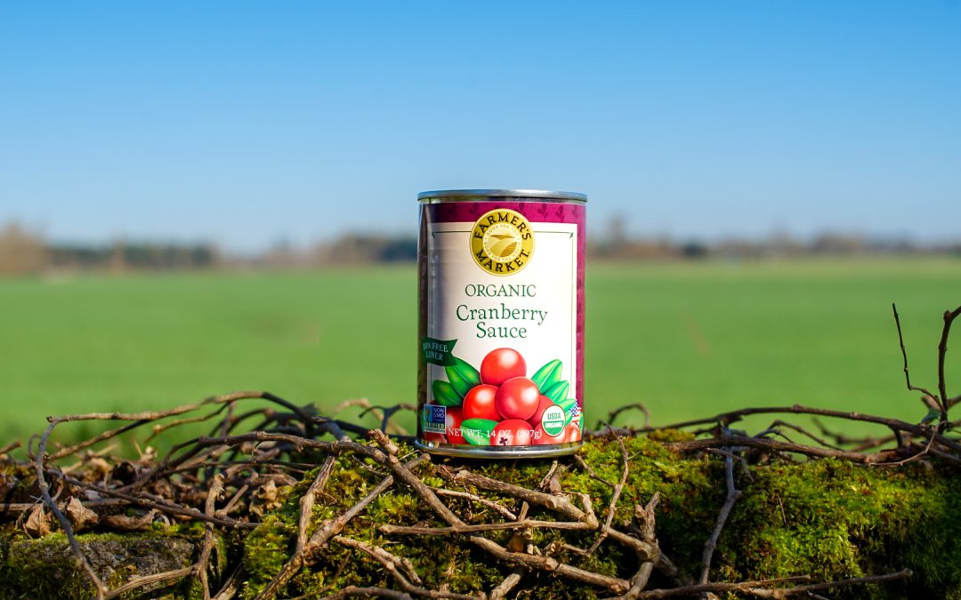 a single can of organic cranberry sauce with a farm back drop