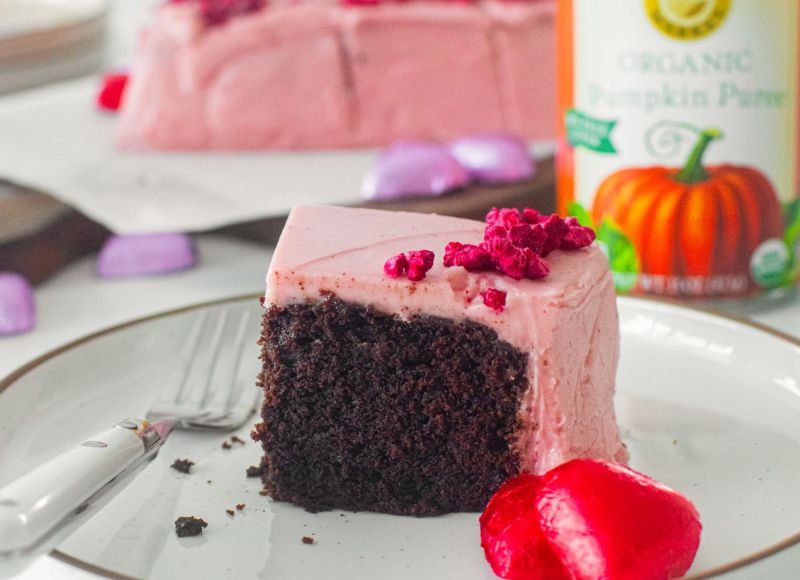 A slice of eggless chocolate cake with raspberry frosting showing a can of Farmer's Market Foods Organic Pumpkin Puree