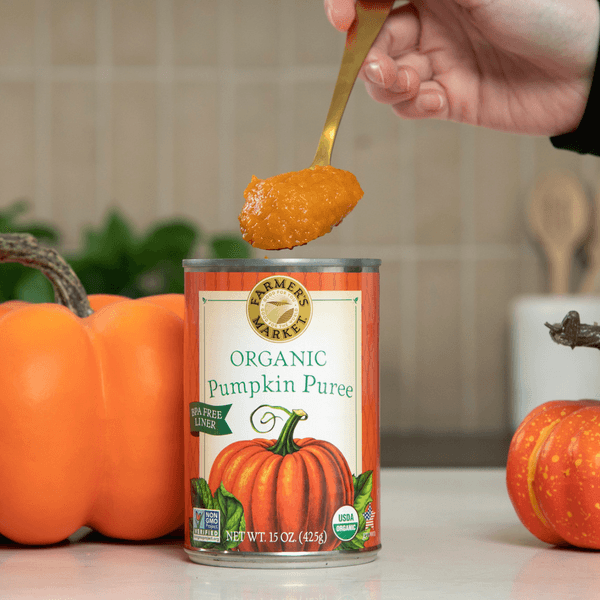 an open can with a scoop of canned pumpkin puree being removed