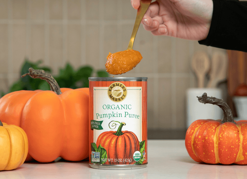 an open can with a scoop of canned pumpkin puree being removed